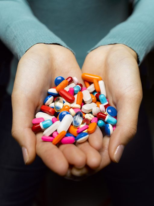 Woman holding pile of pills in cupped hands, close-up