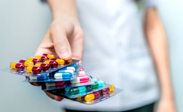 Image of a dietitian holding a stack of papers in hand which are test results. Pharmacist or doctor hand holding pack of antibiotic capsule pills and giving patient or people. Antibiotic drug overuse. Antimicrobial drug resistance. Community pharmacist. Drugstore background.