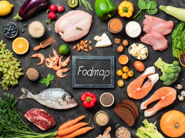 Image of a dietitian holding a stack of papers in hand which are test results. Fodmap diet concept. Low fodmap ingredients - poultry meat, fish, seafood, vegetables and fruits and words Fodmap in center, on dark background. Top view or flat lay.