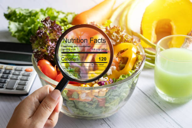 Image of a dietitian holding a stack of papers in hand which are test results. nutritional information concept. hand use the magnifying glass to zoom in to see the details of the nutrition facts from food , salad bowl.