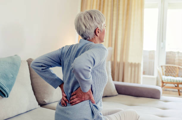 Image of an antimicrobial sitting on a table. Woman feels back pain, massaging aching muscles. Mature woman feeling morning discomfort in aching back in the living room.