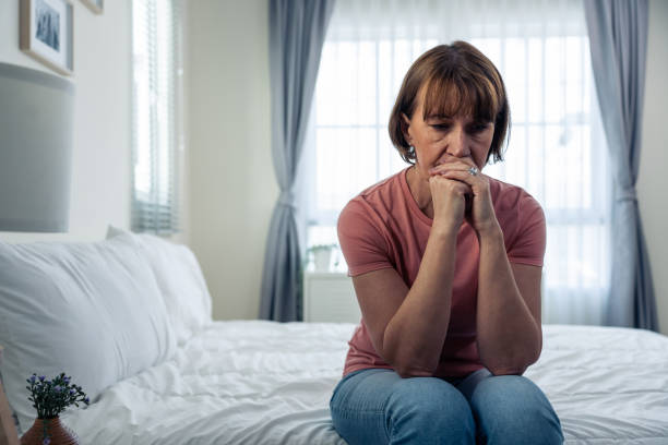 Image of an antimicrobial sitting on a table. Caucasian mature woman frustrating while sit alone on bed in bedroom. Attractive old female upset depressed feel infuriating, sad and upset with life problem in house. Health care Medical Concept.