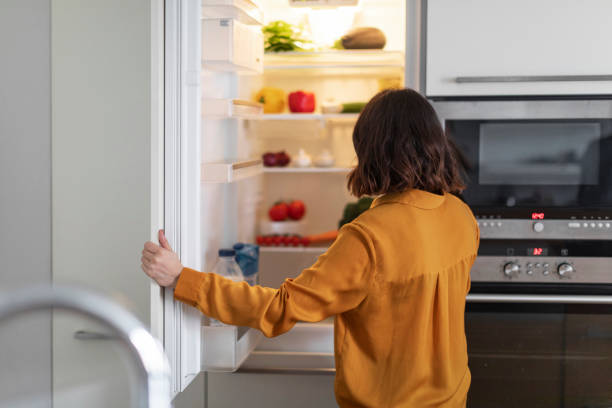 Image of a dietitian holding a stack of papers in hand which are test results. Unrecognizable Young Woman Opening Fridge In Kitchen And Looking Inside, Hungry Brunette Lady Standing Near Open Refrigerator At Home, Starving Female Checking Food Or Drinks, Free Space