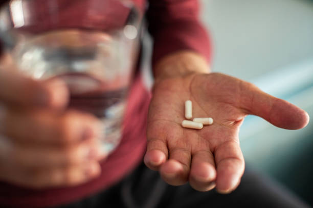 Close up of a senior man taking medicine in a bathroom