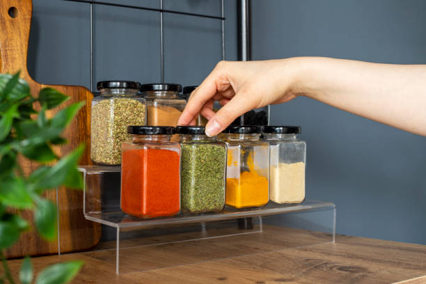 Image of a dietitian holding a stack of papers in hand which are test results. Cropped hand holding jar of spices on kitchen.