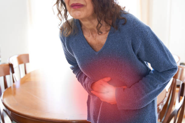 photo of large intestine is on the senior woman body against gray background, People With Stomach ache problem concept, Female anatomy Stomachache and digestive problems. Senior female pressing hands on stomach with painful cramps