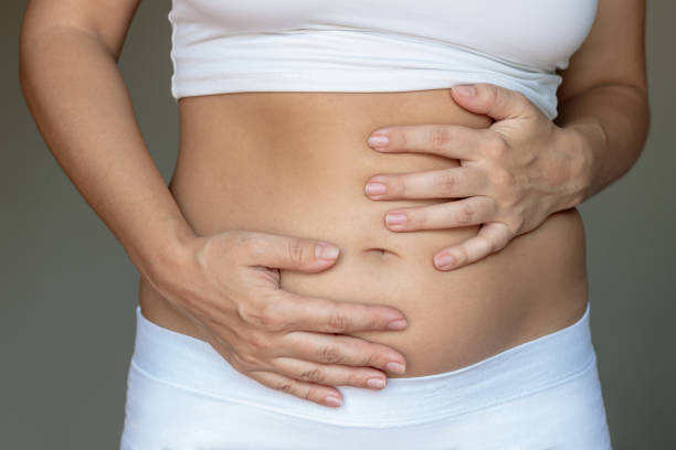 Image of a dietitian holding a stack of papers in hand which are test results. Stomach ache, bloating, flatulence, abdominal distension, colic, digestive disorders. A young woman holding her stomach with her hands on a dark gray background. Overeating, overweight, excess weight