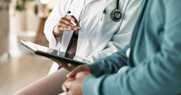 Image of a dietitian holding a stack of papers in hand which are test results. Tablet, hands and patient with doctor in hospital for consultation with cold, flu and sickness. Digital technology, conversation and person with healthcare worker for medical diagnosis in clinic.