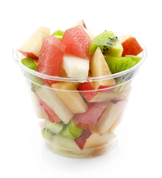 Image of an antimicrobial sitting on a table. fresh fruit pieces salad in plastic glass isolated on white background