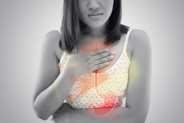 Image of a dietitian holding a stack of papers in hand which are test results. Woman suffering from Acid reflux or Heartburn against gray background / Asian people with symptomatic Indigestion or Gastritis