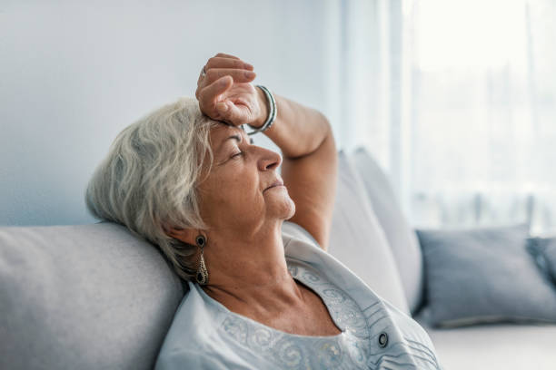 Image of a dietitian holding a stack of papers in hand which are test results. Fatigued senior woman relaxing on bed. Senior woman relaxing at home. Woman having a nap on the sofa relaxing with her head tilted back on the cushion and eyes closed