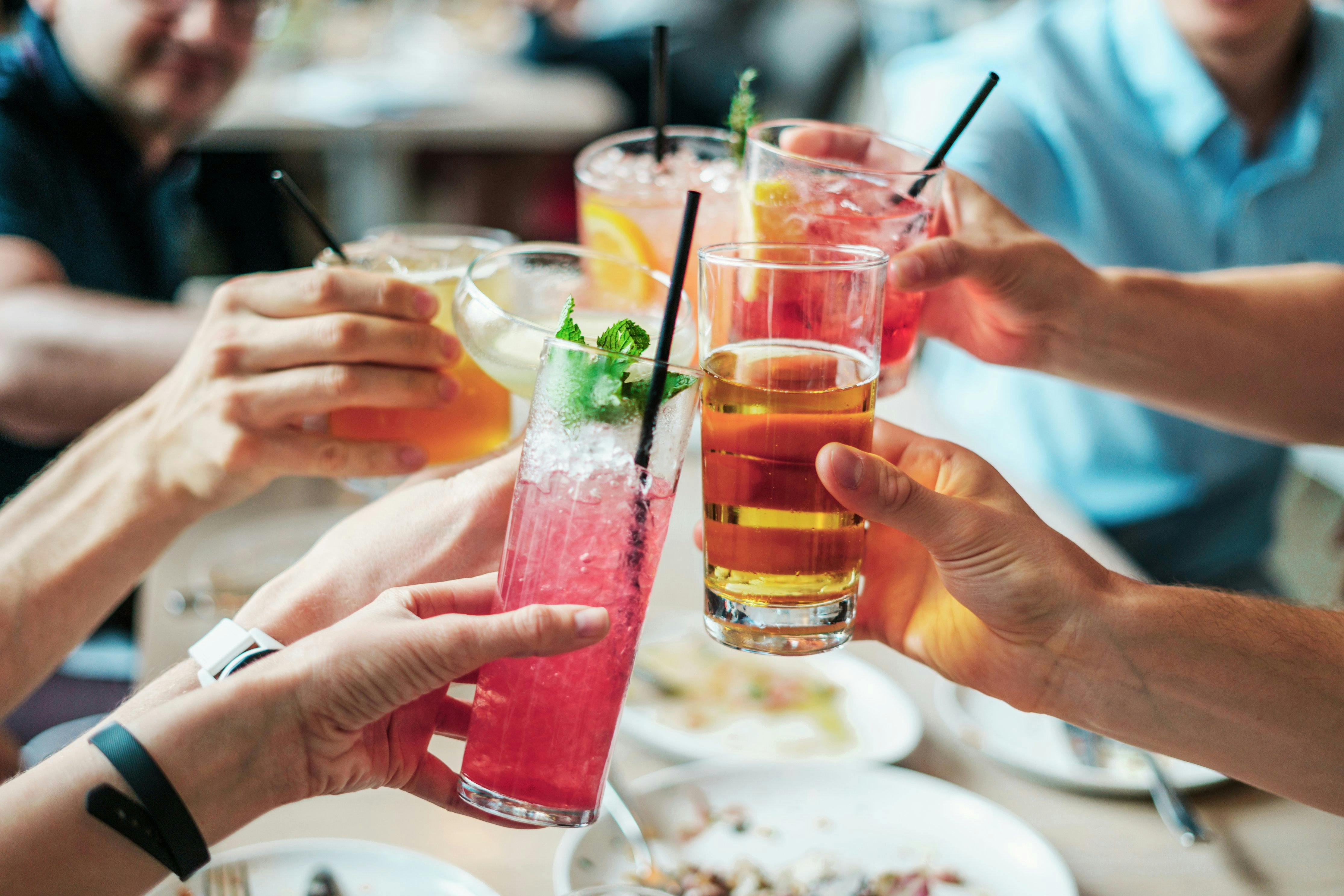 Image of a dietitian holding a stack of papers in hand which are test results. People cheering with alcohol drinks.